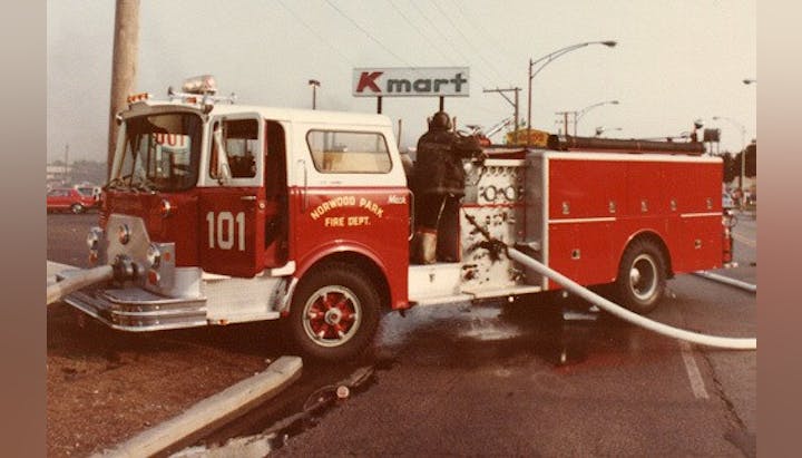 Fire truck with firefighter working, park near Kmart store.