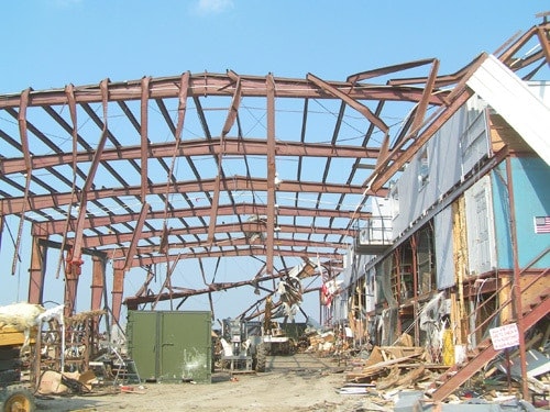 A partially collapsed metal structure and debris, with clear blue sky.