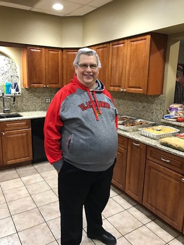 A person in a kitchen, wearing a Blackhawks hoodie, standing in front of a counter with various dishes.