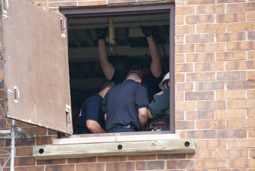 Several people inside a building near an open window, appearing to be working or setting something up.