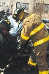 Firefighters in gear working near a vehicle.
