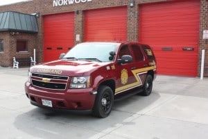 A red fire department SUV is parked in front of a building with red garage doors.