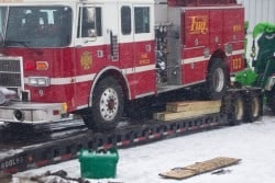 A fire truck is loaded on a flatbed trailer with snow on the ground.