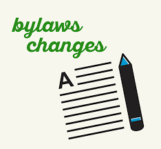 Illustration with the words "bylaws changes" in green text above a stylized image of a document with the letter "A" and horizontal lines, next to a large pencil. The image represents amendments or revisions to organizational bylaws.