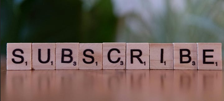 Tiles spelling "SUBSCRIBE" on a reflective surface.