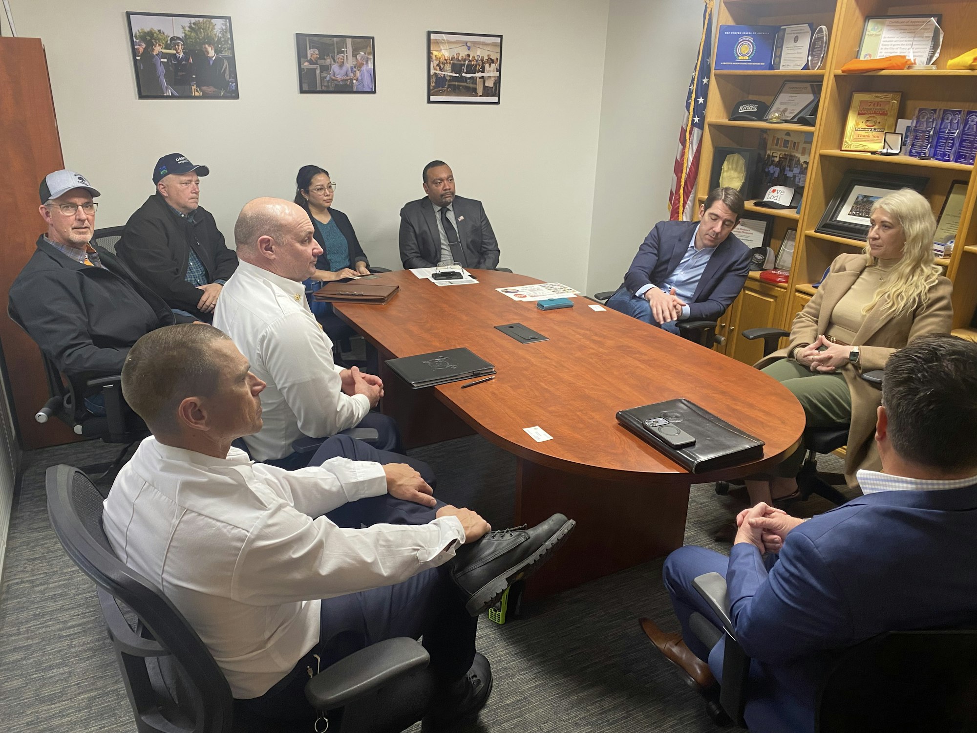 A group of people seated around a conference table in a meeting, discussing various topics in an office setting.