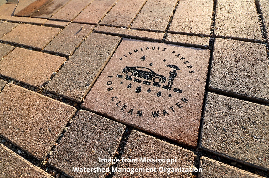 Pavement with a special brick promoting permeable pavers for clean water, indicating eco-friendly urban design.