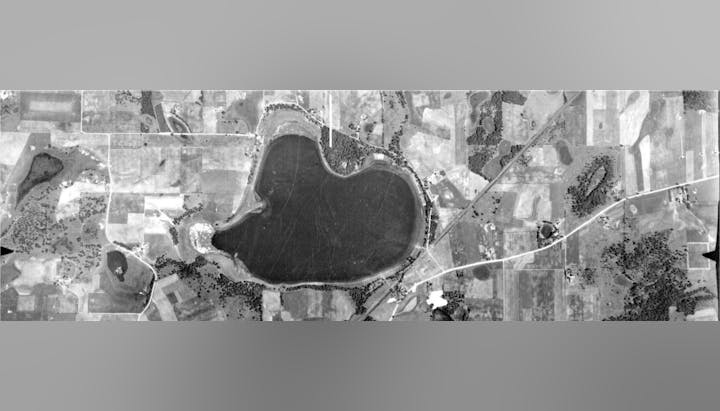 Aerial view of a heart-shaped lake surrounded by fields and roads.