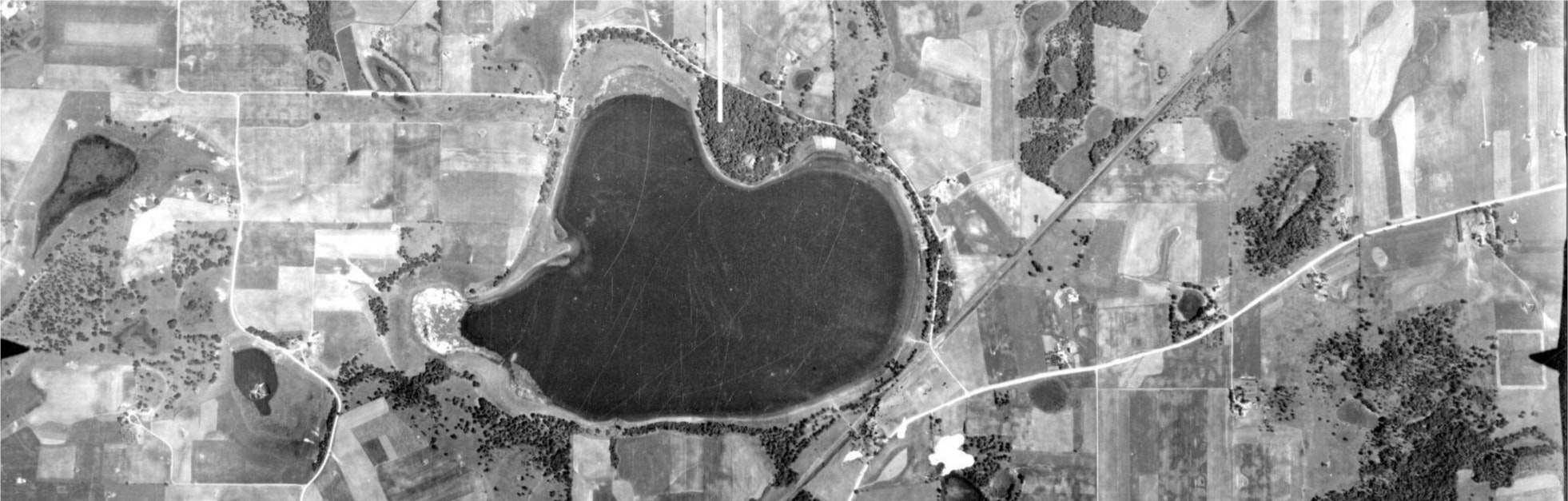 Aerial view of a heart-shaped lake surrounded by fields and roads.
