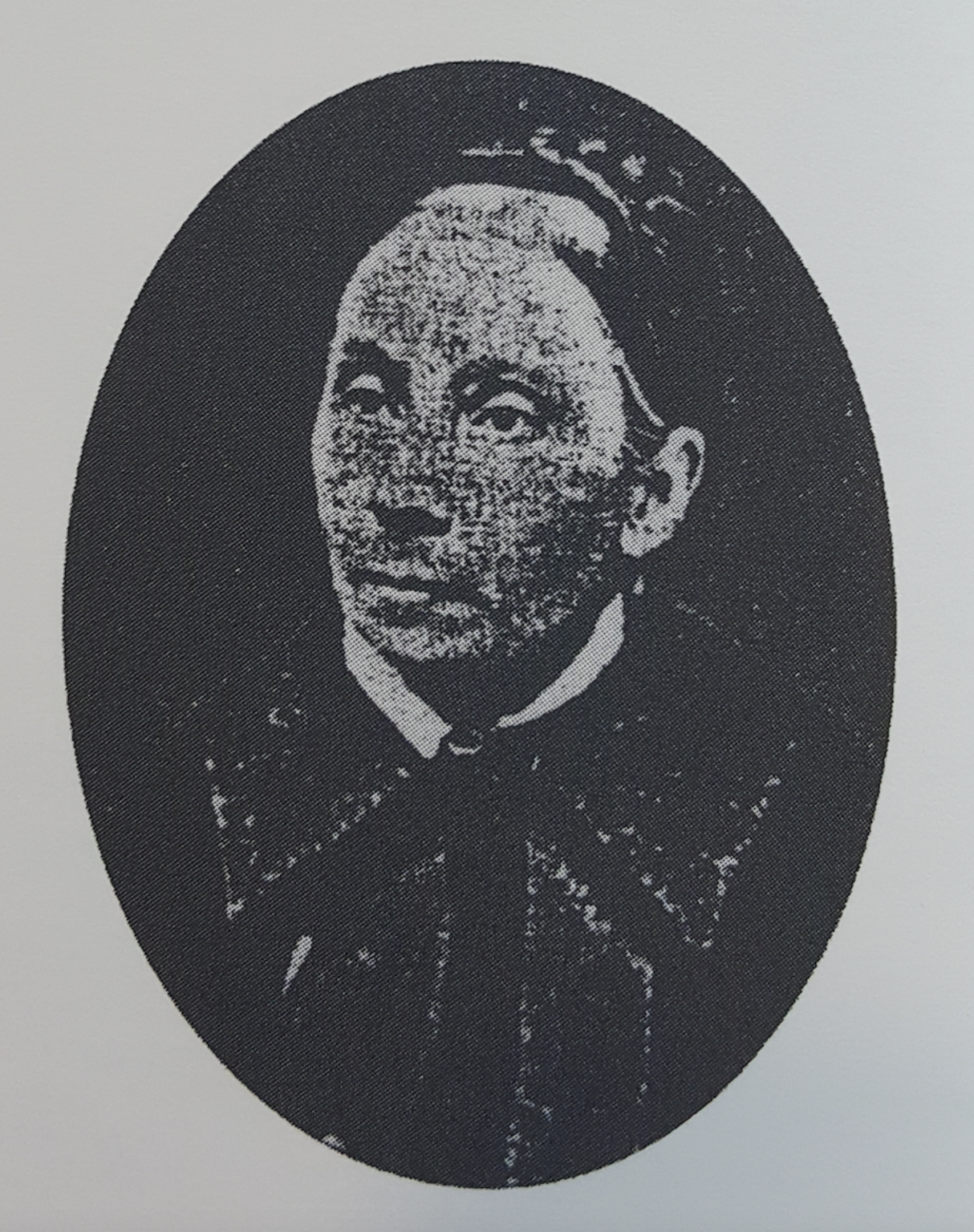 An oval portrait of a person with a clear gaze, featured within a dark frame against a light background.