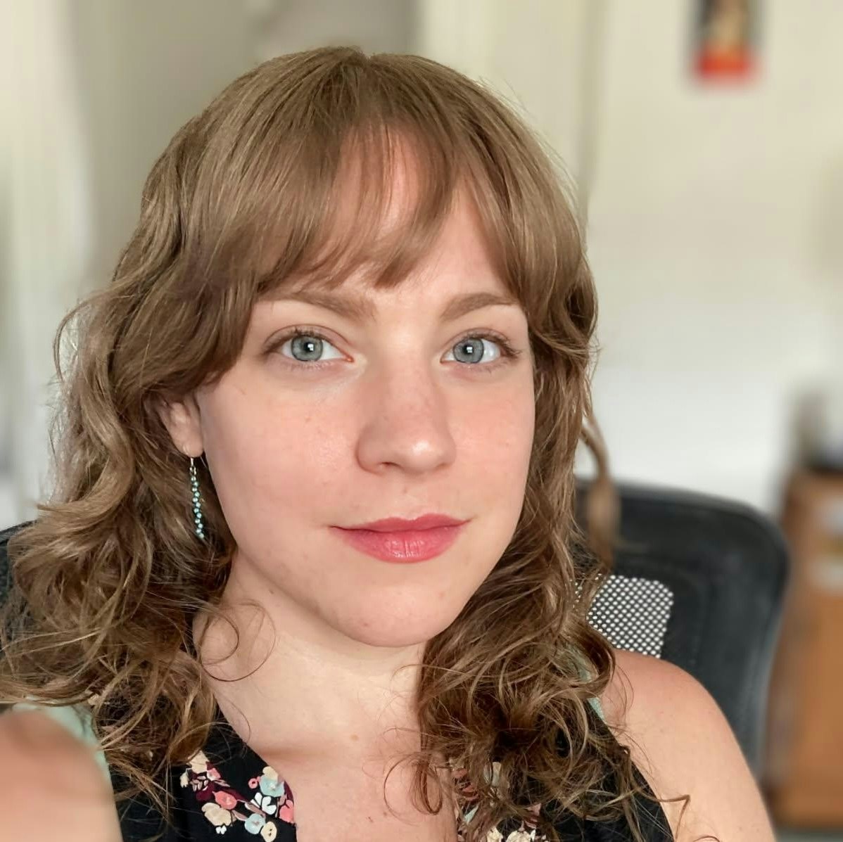 The image features a close-up portrait of a person with curly hair, wearing a floral top, looking directly at the camera.