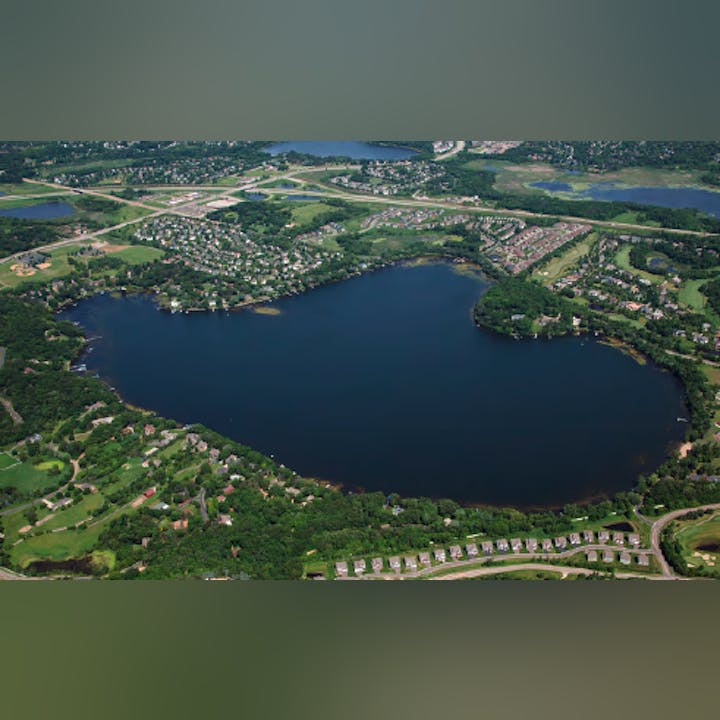 Aerial view of a lake surrounded by residential areas and greenery.