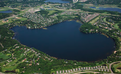 Aerial view of a lake surrounded by residential areas and greenery.