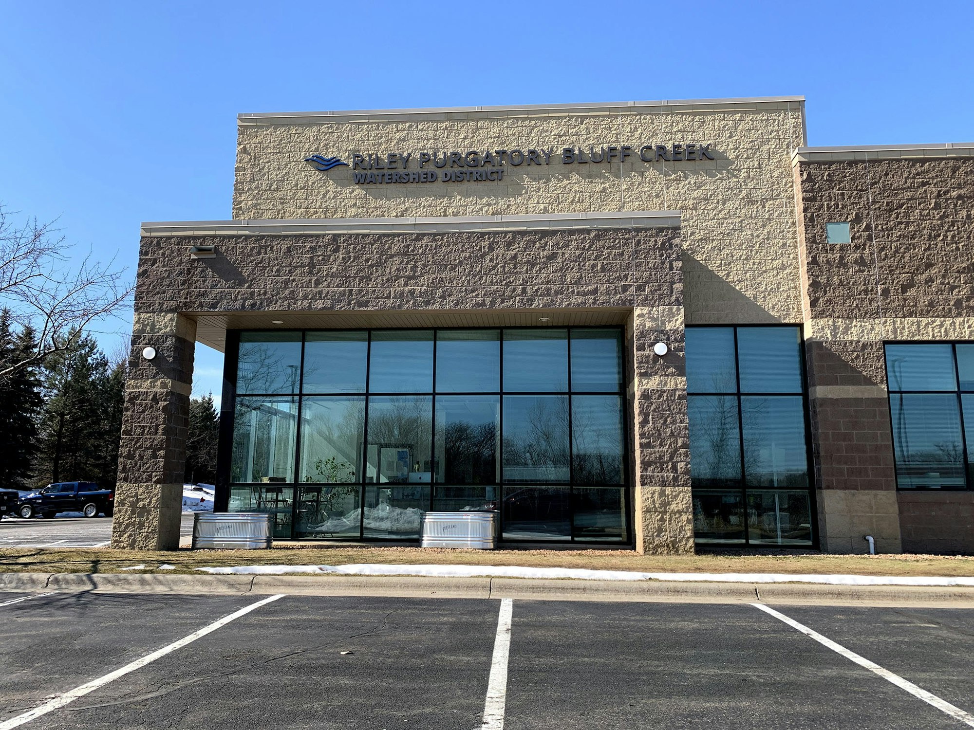 A building with the sign "Riley Purgatory Bluff Creek Watershed District" under a clear sky.