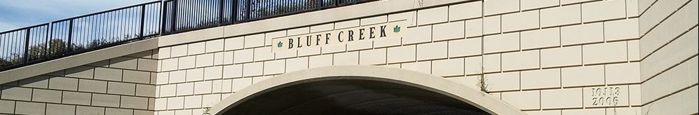 A white bridge with "BLUFF CREEK" text, a leaf symbol, and the years "2003 2006" on its side.