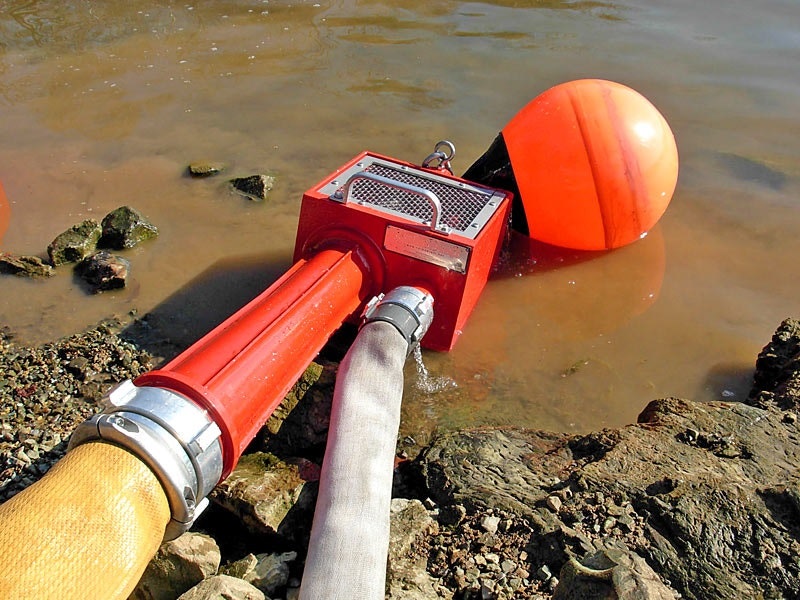 Metal box in a pond with two fire hoses coming out of the box