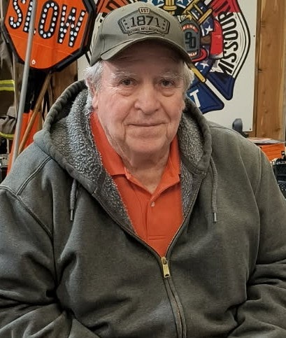 A man in a cap and hoodie jacket in a fire station.