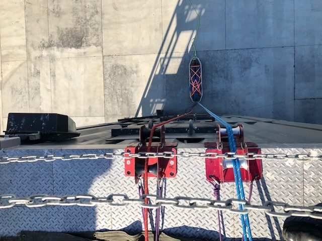 Rope rescue gear at the top of building and a fire fighter and victim are hanging from the ropes and gear and are many stories below.