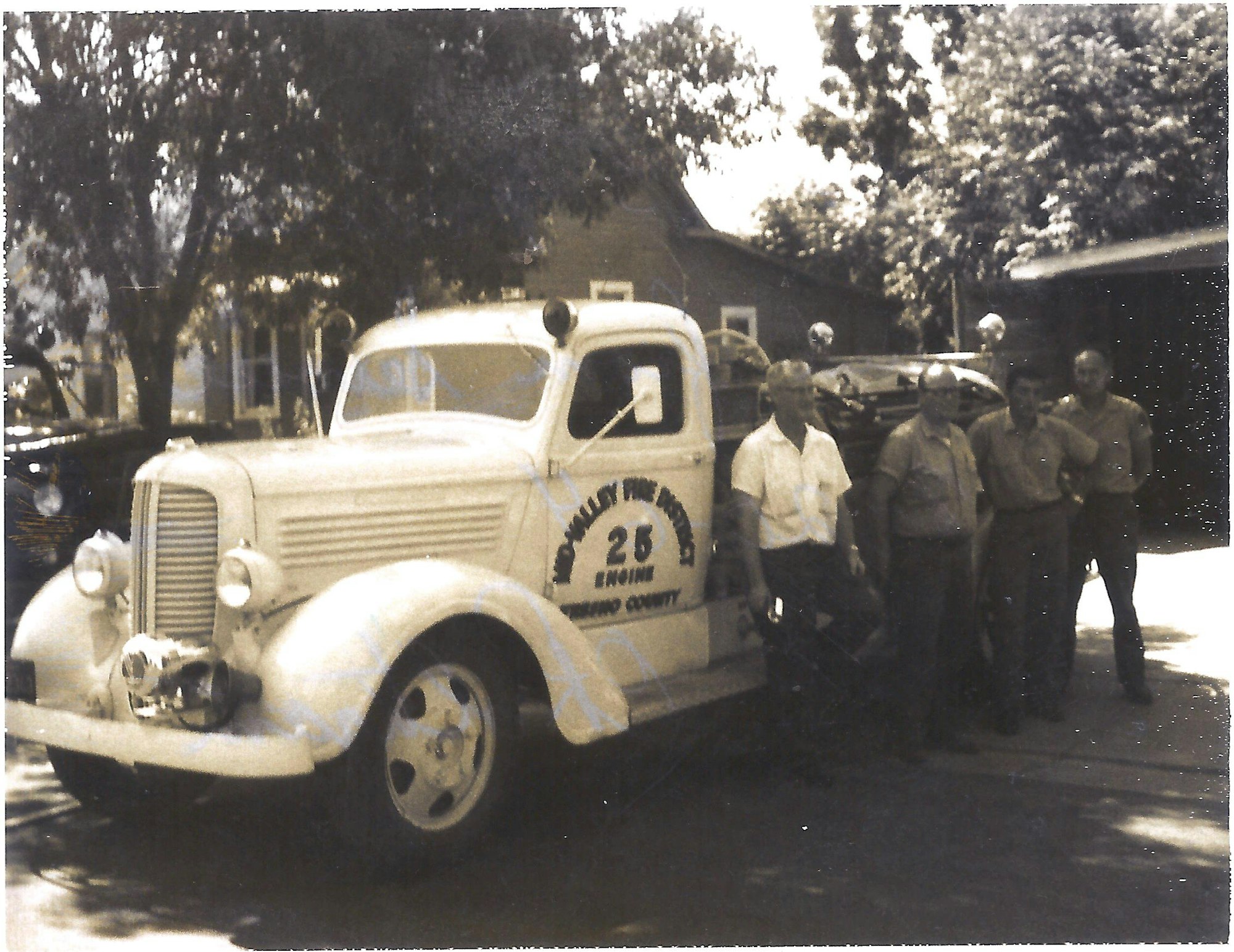 Historical picture of Fire fighters standing in front of 1950's fire truck