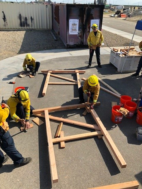 Several firefighters are working to build a wood framed shore used to stabilize a compromised door