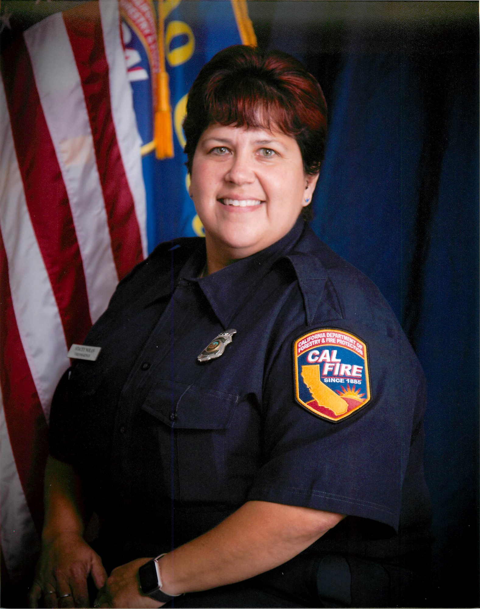 CAL FIRE Fresno County Fire Board fire prevention specialist in uniform with department and American flag in background