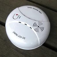 A carbon monoxide detector on a wooden surface.