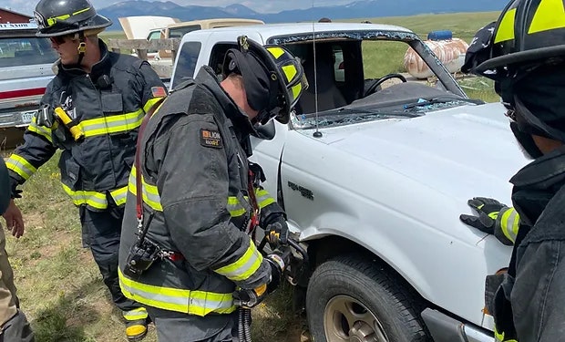 Firefighters working on a damaged vehicle, likely during a rescue operation.