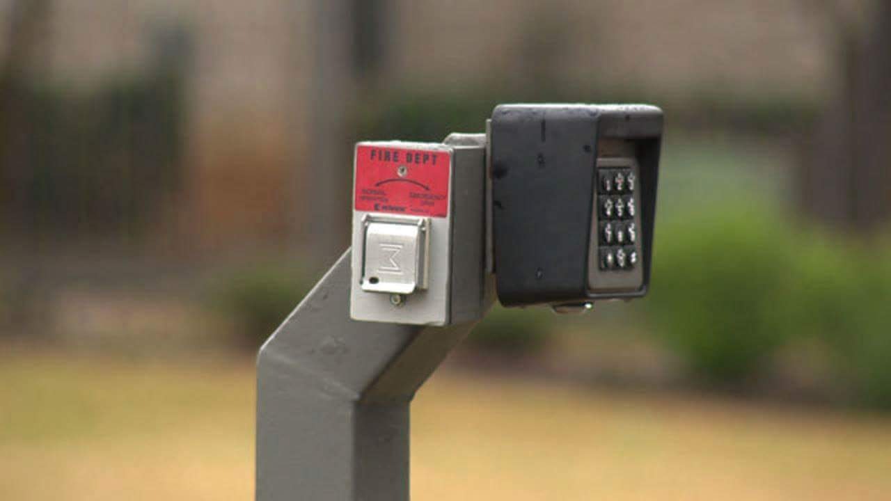 A fire department connection lock box with a keypad, mounted on a post.