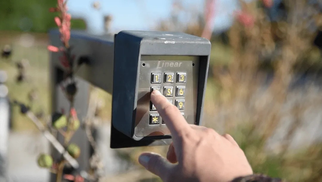 A person's hand pressing buttons on a keypad entry system.