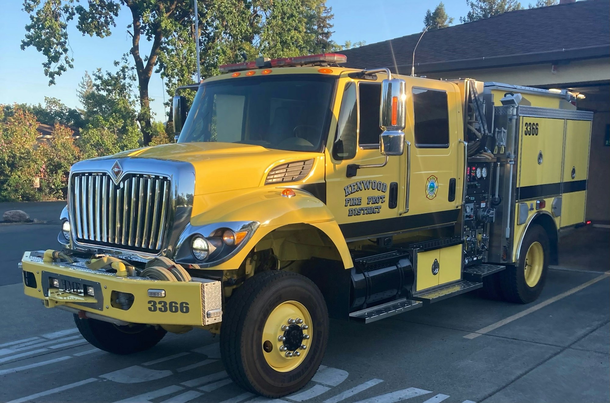 A yellow fire truck parked, labeled "Kenwood Fire Prot. District," with equipment visible.
