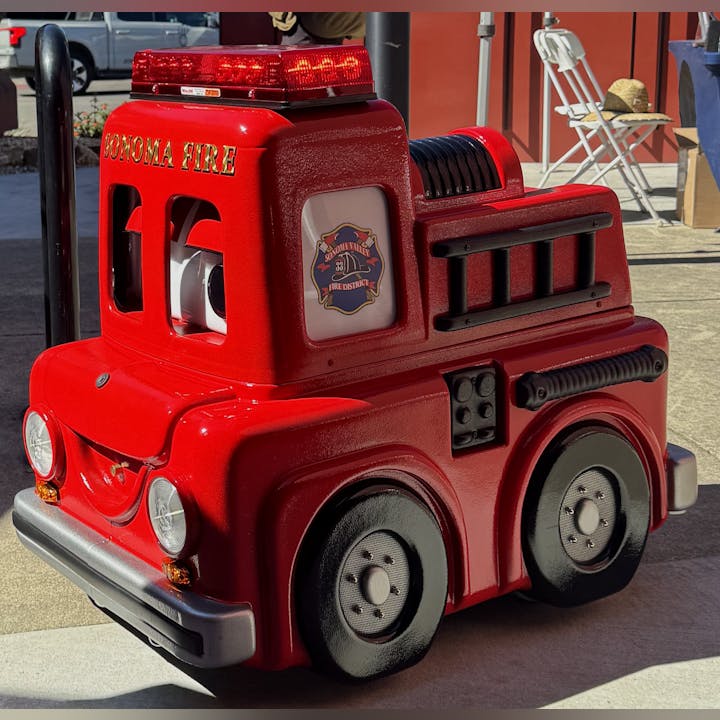 A red children's fire truck ride with "Sonoma Fire" and "Sonoma Valley Fire District" labels.