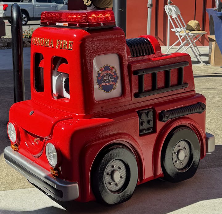 A red children's fire truck ride with "Sonoma Fire" and "Sonoma Valley Fire District" labels.