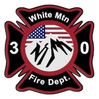 A fire department emblem with mountains, an American flag, and the text "White Mtn Fire Dept. 3 0."