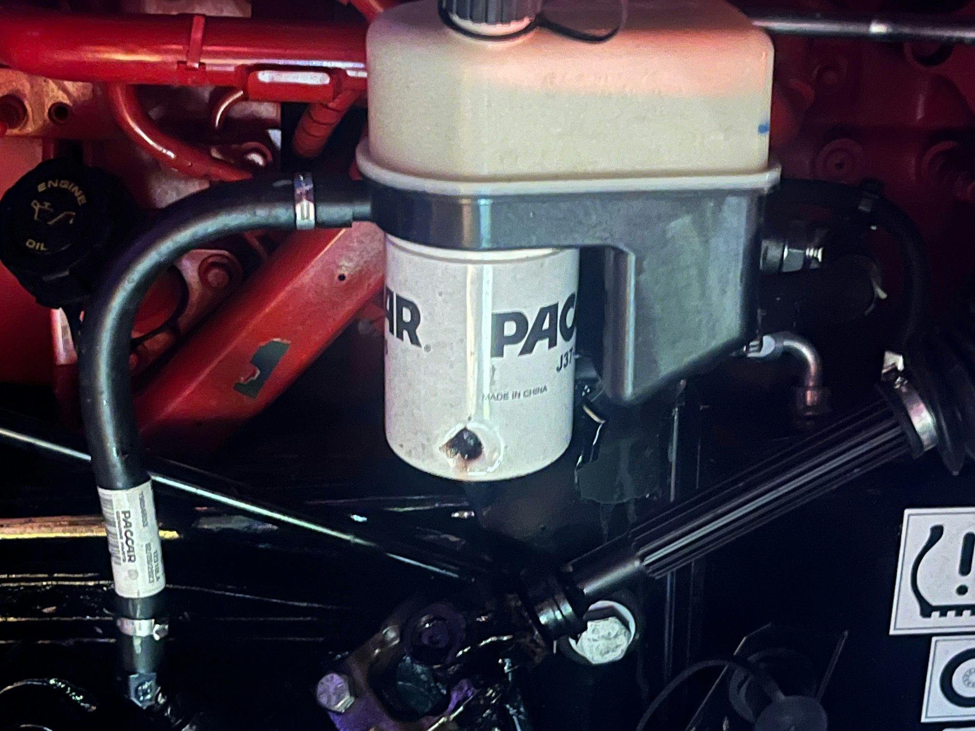 Engine section showing a PACCAR fuel filter, pipes, engine oil cap, and mechanical components.