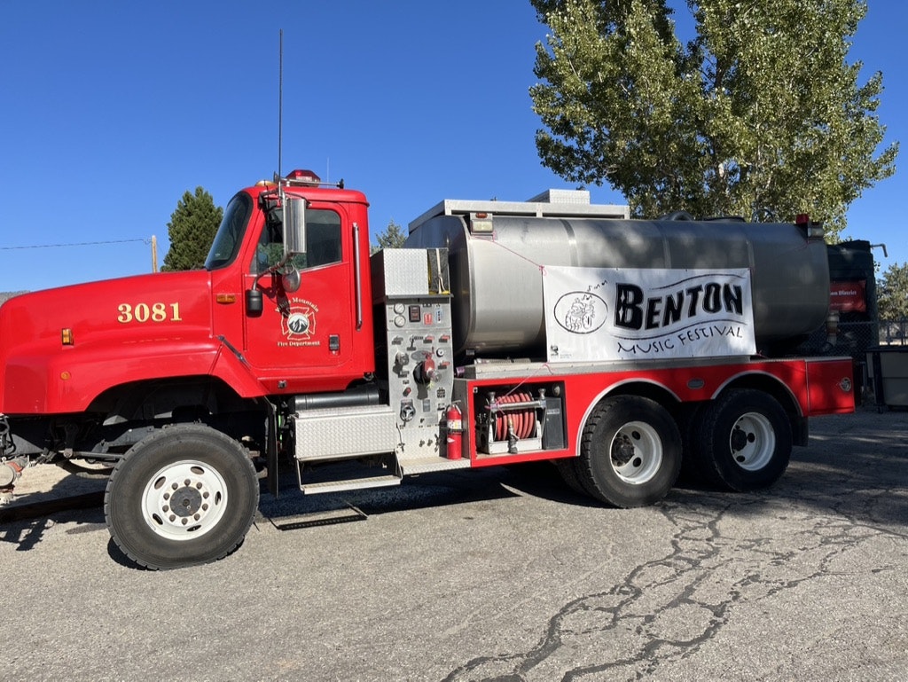 A red fire truck with a sign for "Benton Music Festival" displayed on its side.