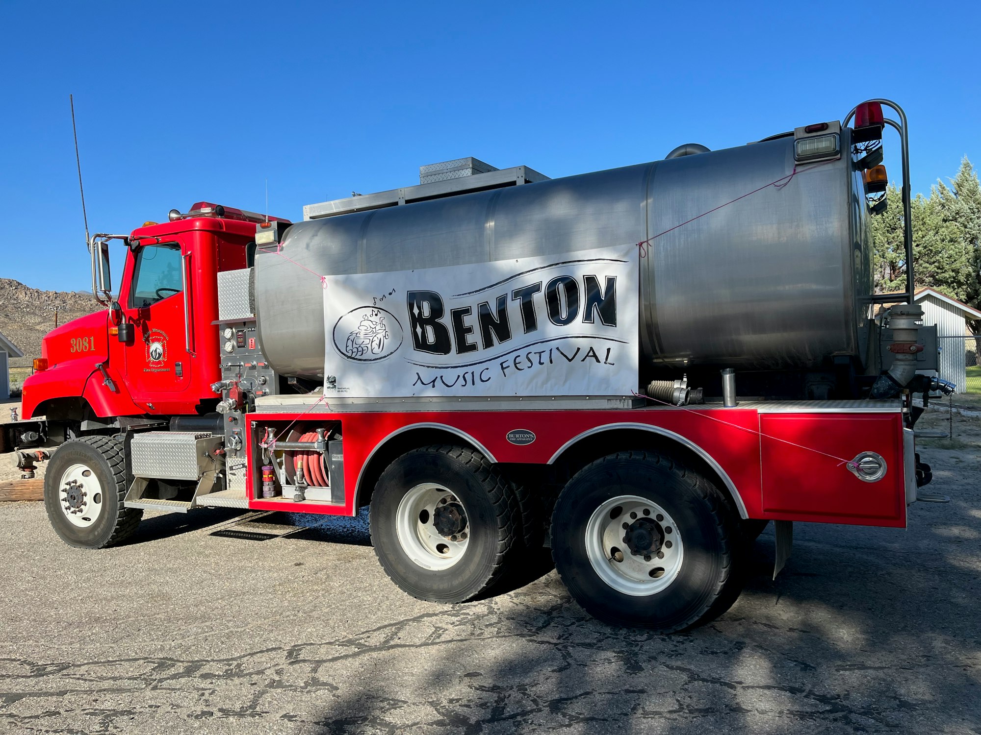 A red tanker truck with a "Benton Music Festival" banner on its side.