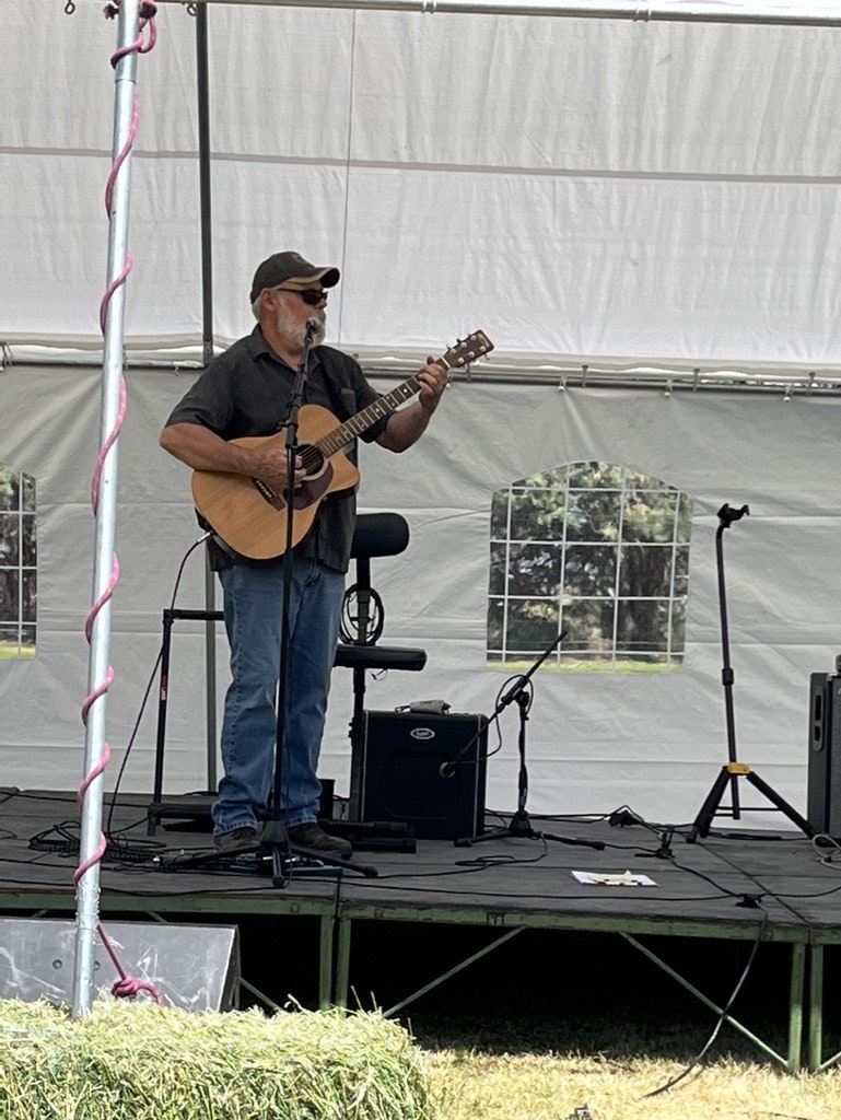 A person playing guitar on a stage with audio equipment.