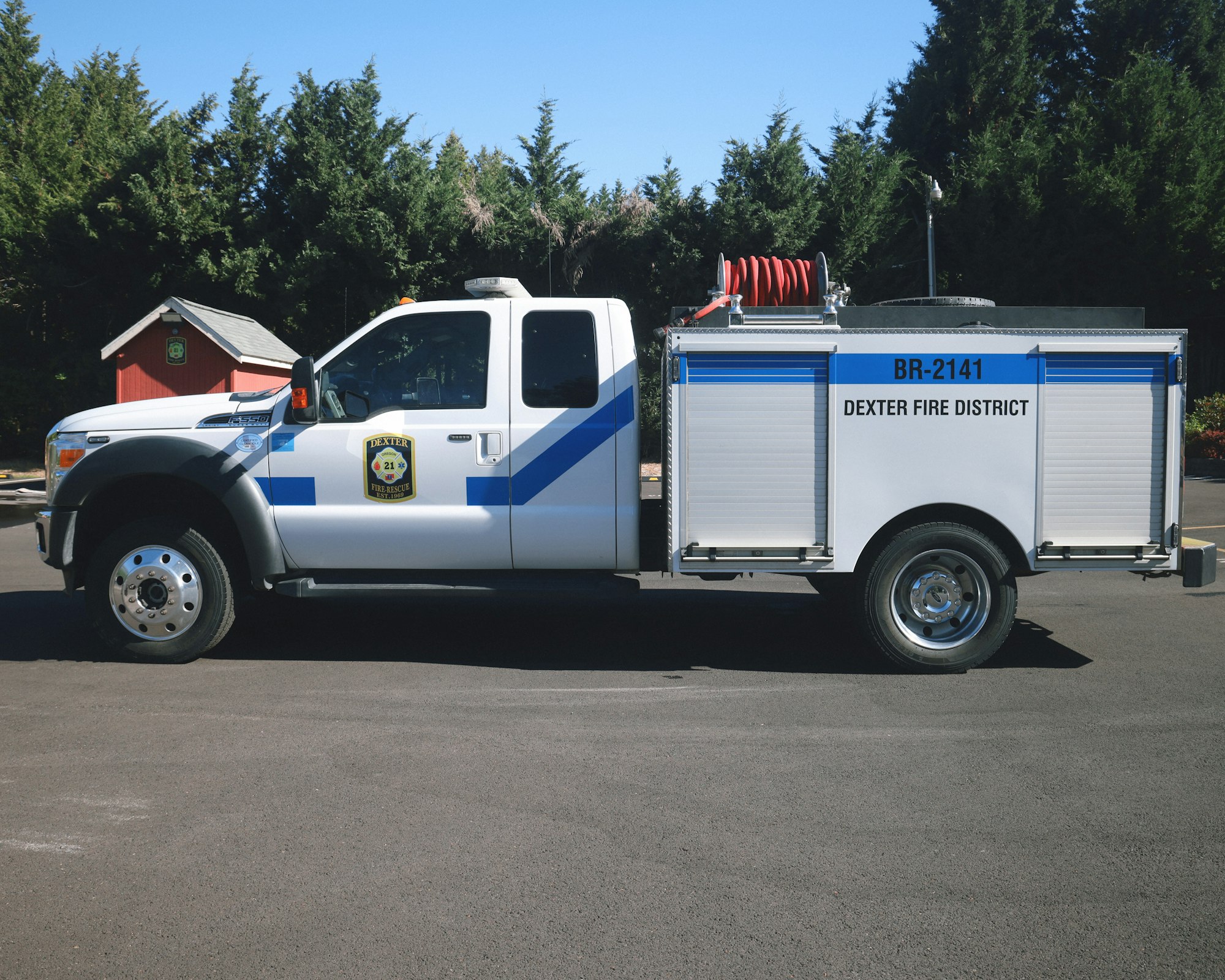 A white fire truck labeled "Dexter Fire District" parked on a road, surrounded by trees.