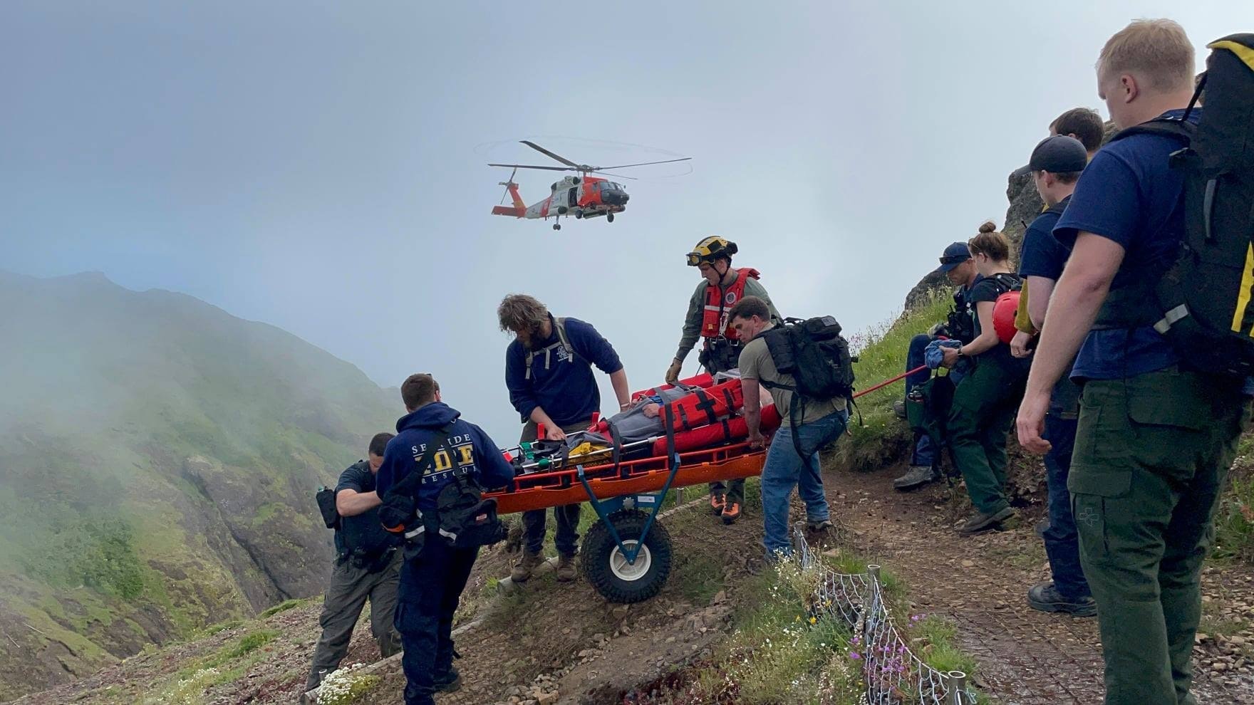 Rescue team with stretcher and helicopter on misty mountain.