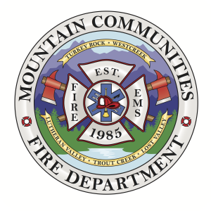The image features the emblem of the Mountain Communities Fire Department, established in 1985, with symbolic elements like axes and mountains.