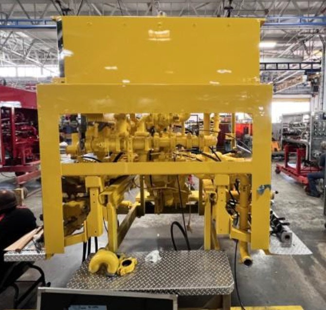 Yellow machinery or equipment in an industrial workshop, with various mechanical components visible.