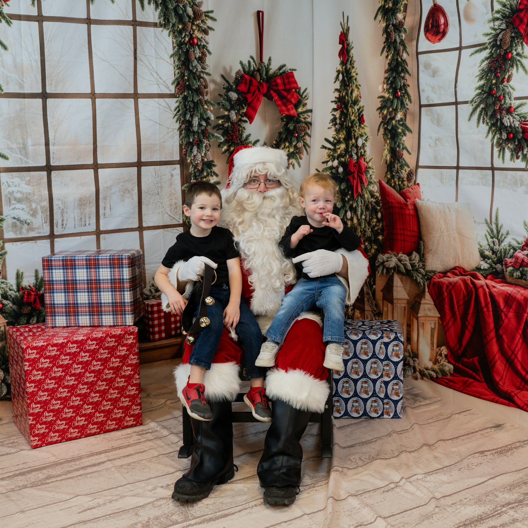 Santa sitting with two children on his lap, surrounded by Christmas decorations and gifts.