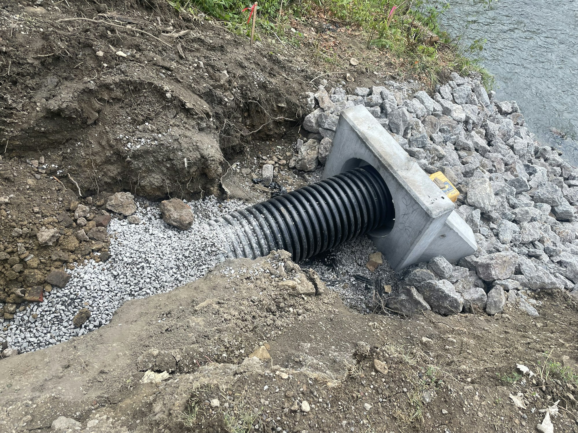A culvert pipe with a concrete headwall installed in an embankment for water drainage.