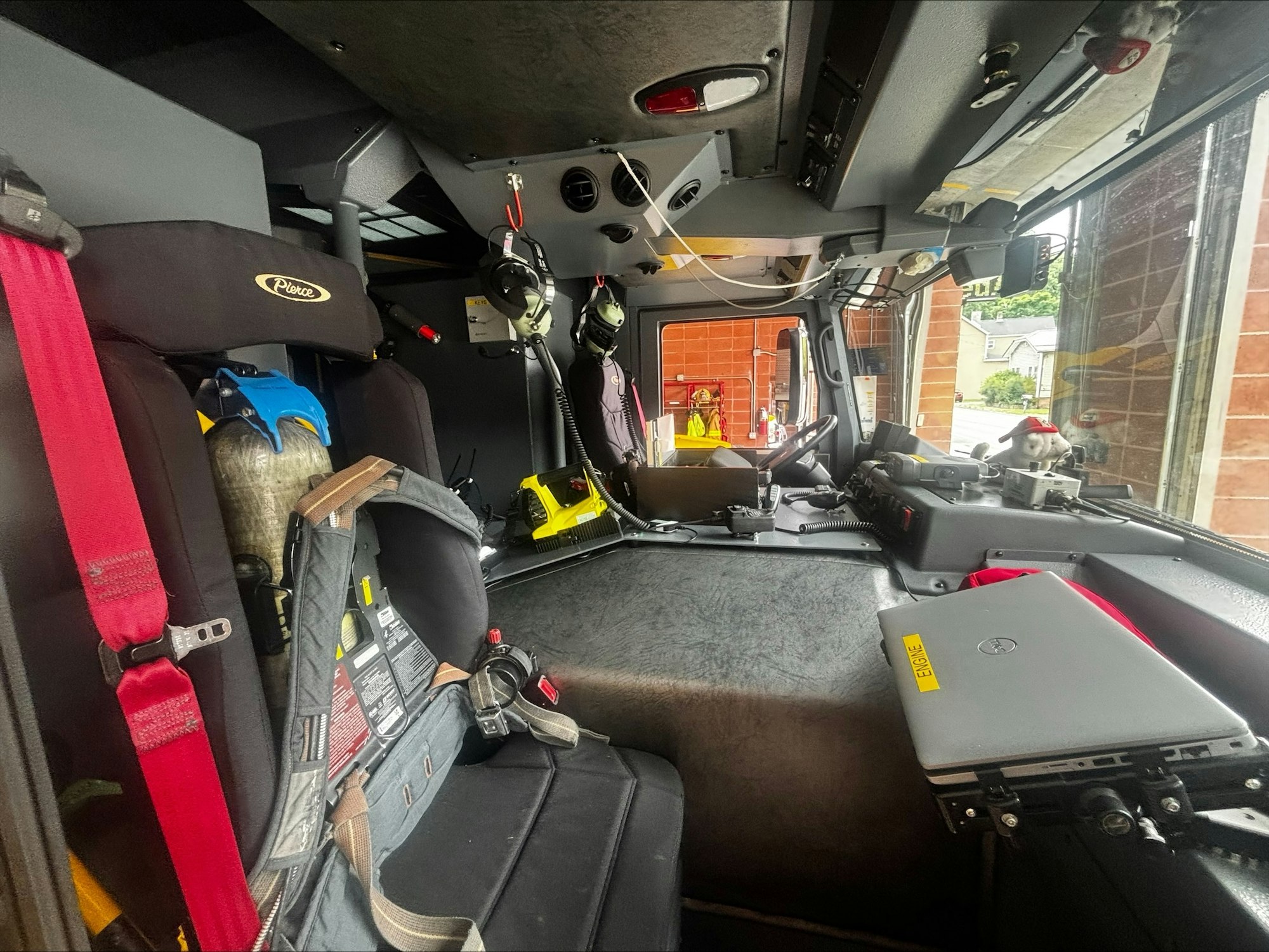 The image shows the interior of a fire truck with seats, safety equipment, and a laptop, suggesting readiness for emergency response.