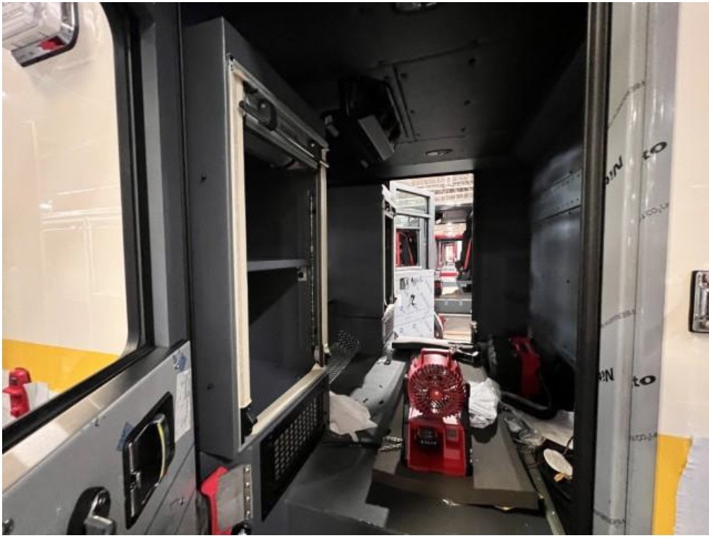 Interior of a vehicle with a red fan, partially open compartments, and packing materials on the floor.