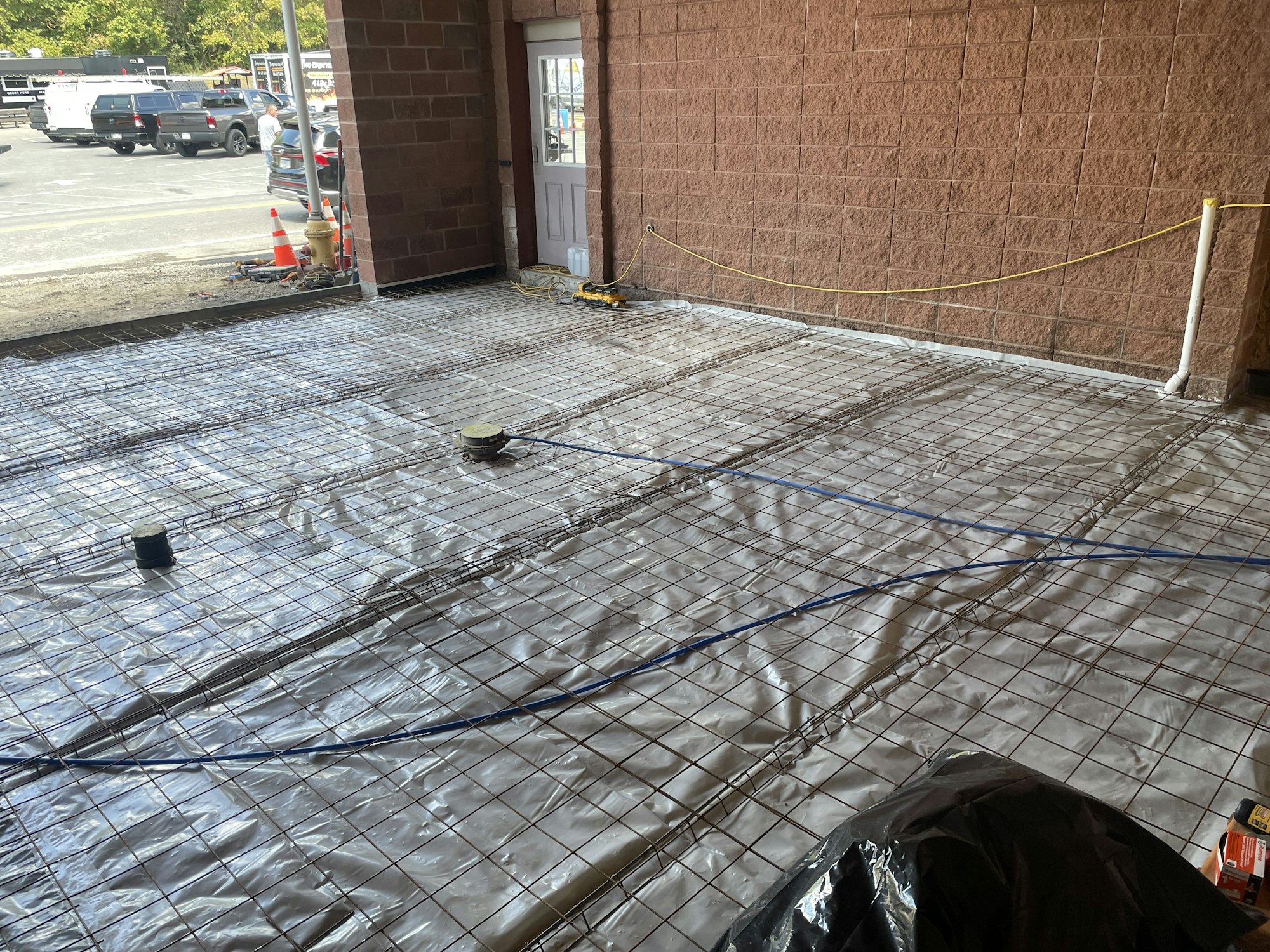 A construction site with reinforced steel bars laid out on a covered floor, prepping for a concrete pour.