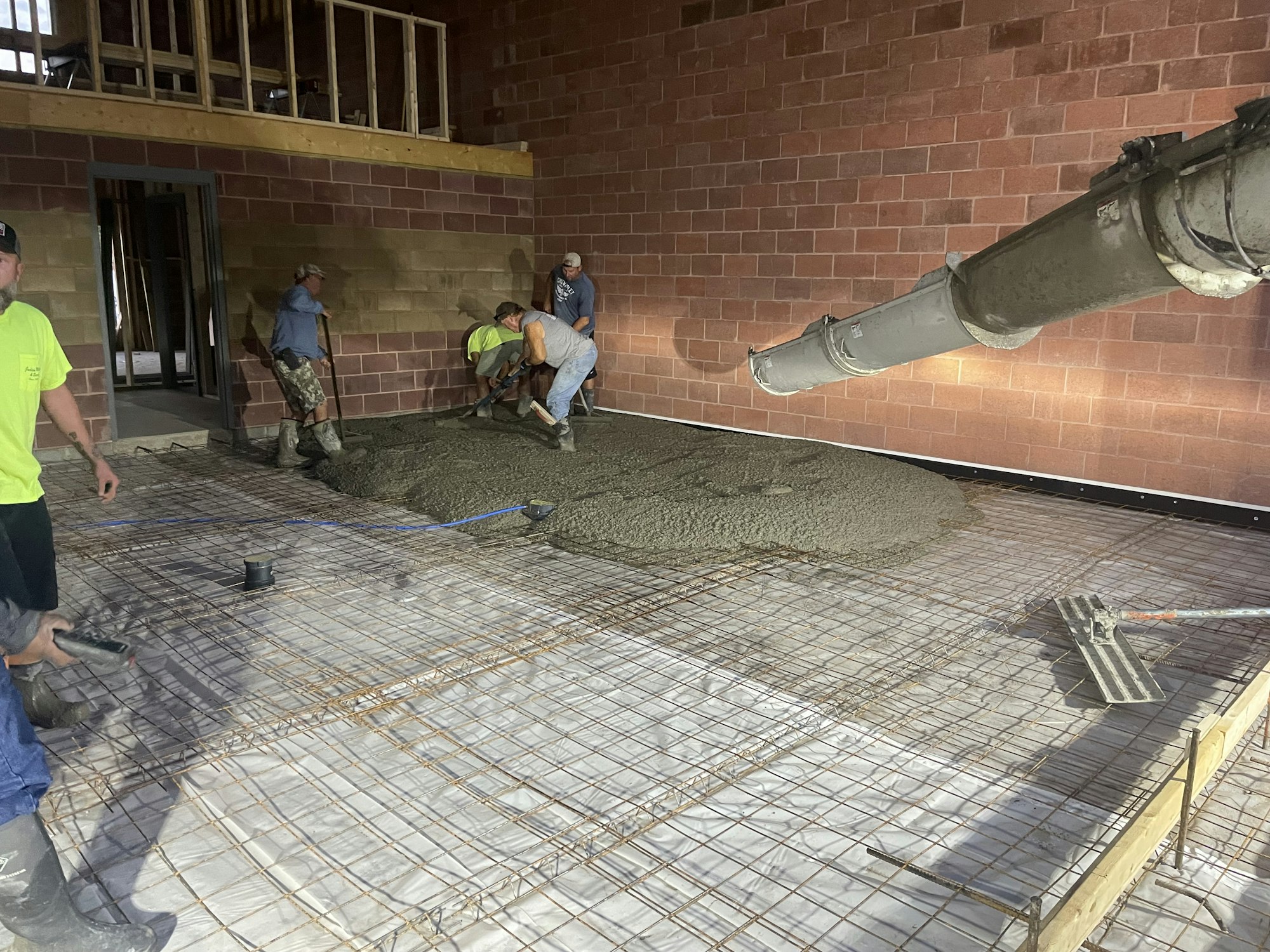 Workers pouring concrete over rebar on a construction site with a concrete pump.