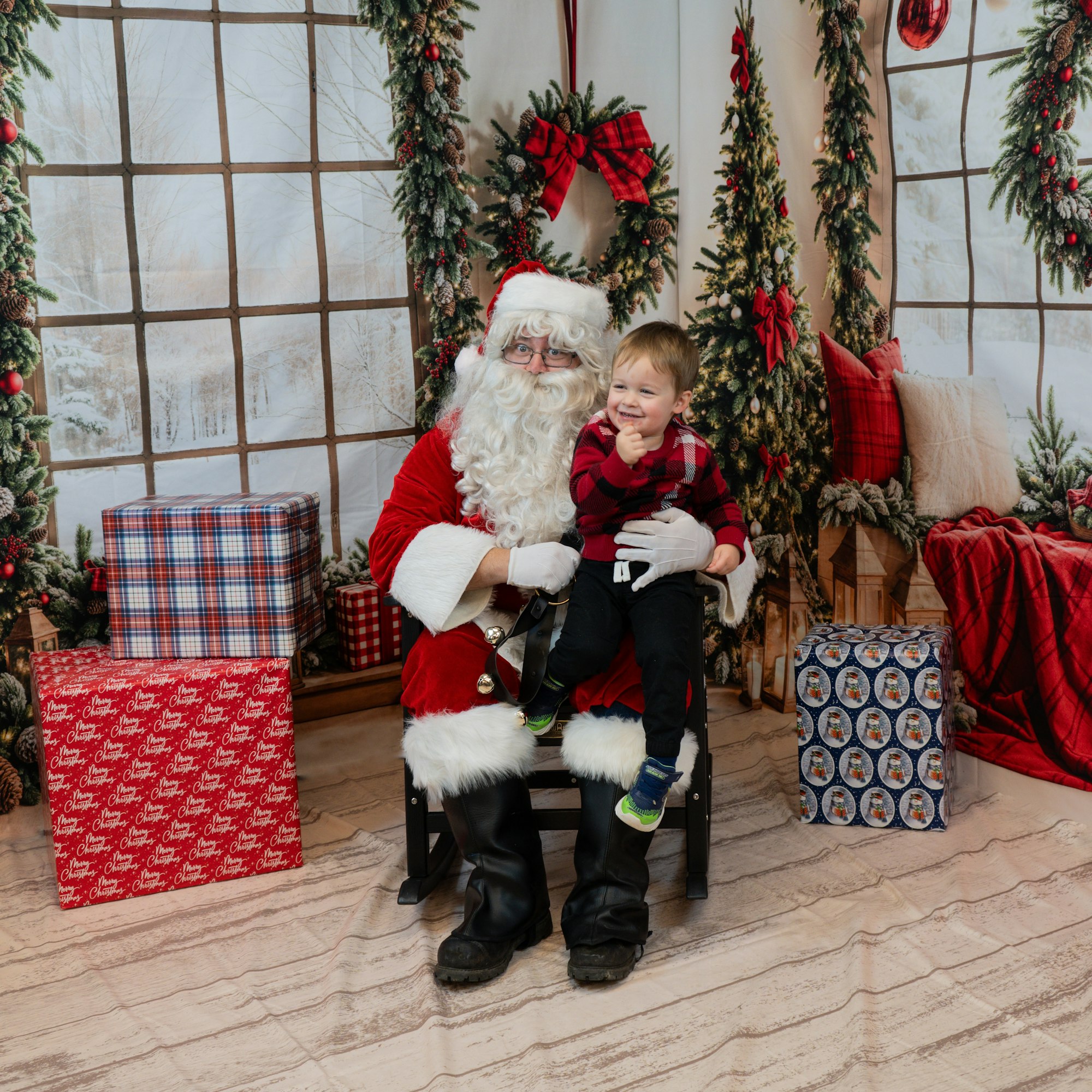 Santa with a child on his lap, surrounded by Christmas decorations and presents.