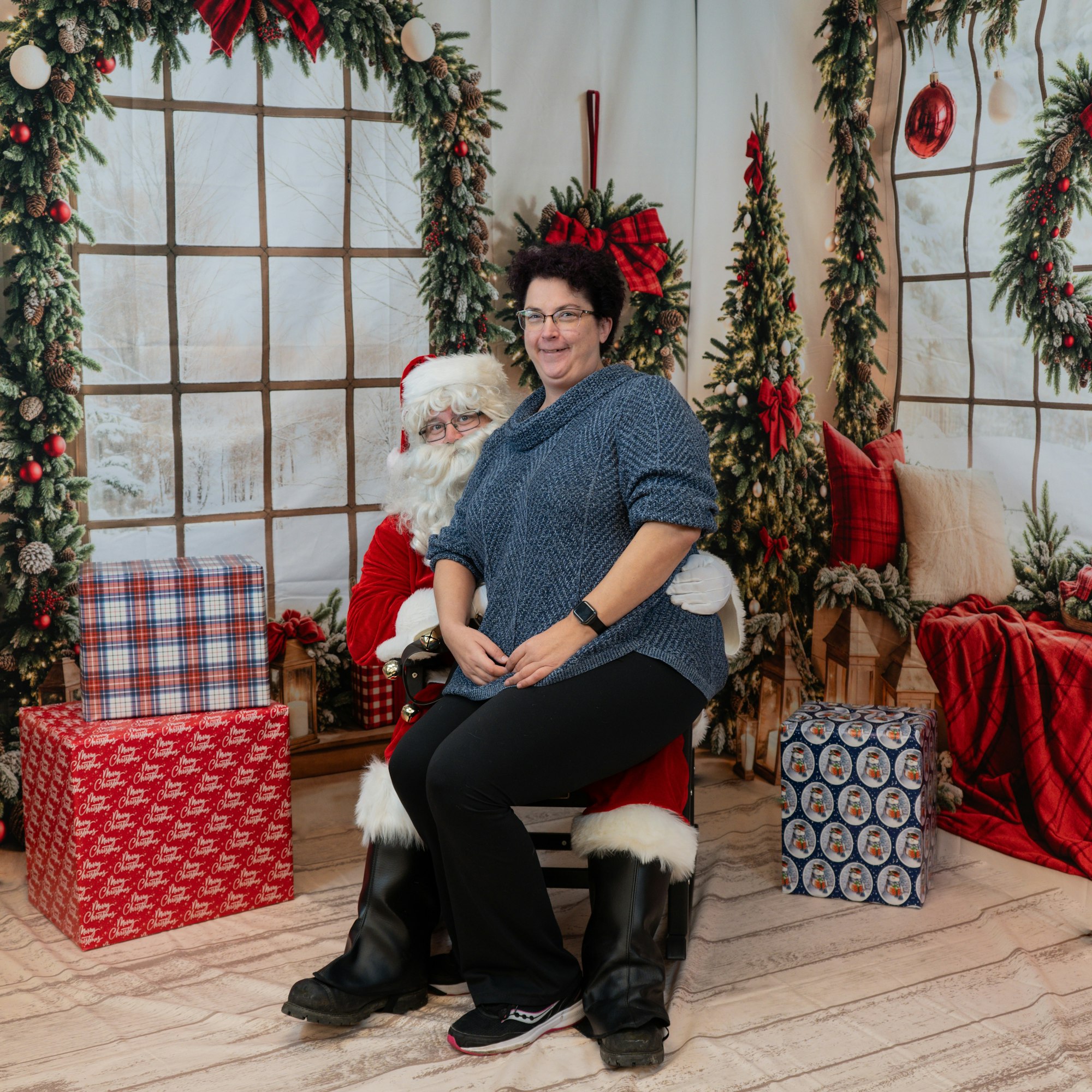 A person sitting on Santa's lap in a Christmas-themed setting with decorations and wrapped gifts.