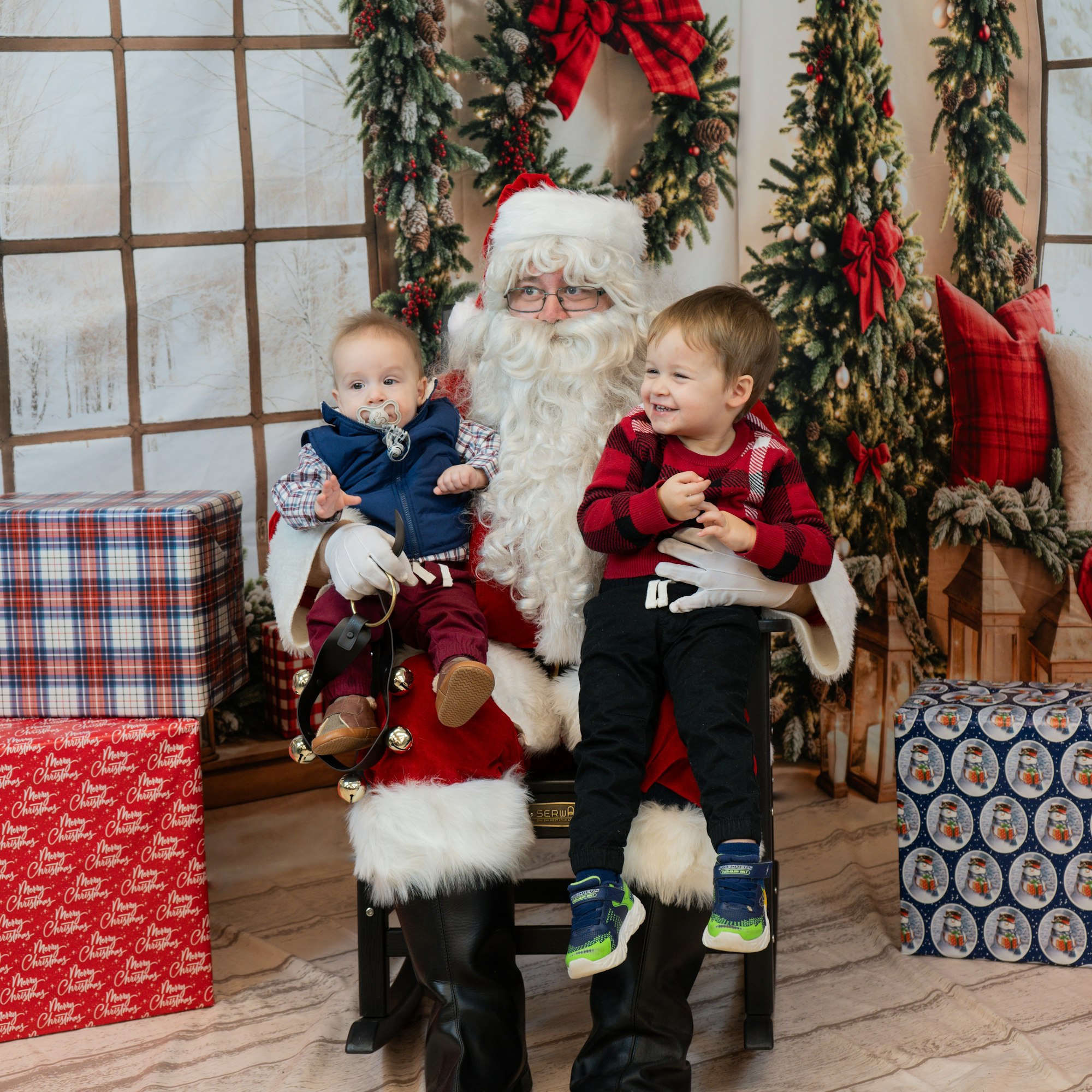 Santa with two kids on his lap, surrounded by Christmas decorations and gifts.